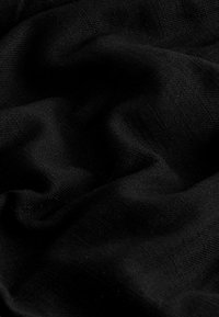 Tissu noir avec une surface lisse et légèrement texturée, présentant des plis doux et une finition uniforme. Aucun motif ni accent visible.