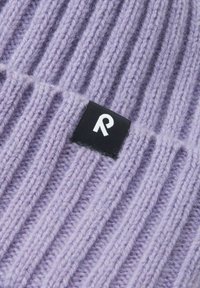 Lilac ribbed knit beanie with a textured surface and a black label featuring a white logo, positioned prominently on the front.