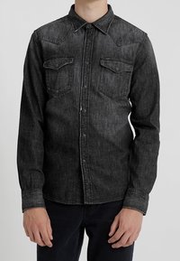 Svart denimskjorta med långa ärmar, spetskrage, västerländsk stil på axeln, två bröstfickor och knappstängning fram. Texturerad tygdesign.