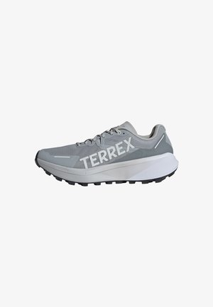 Zapatilla de correr gris con parte superior de malla, gran marca "TERREX", media suela blanca y suela exterior de goma negra. Presenta un diseño con cordones.