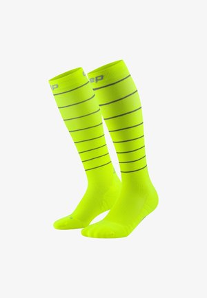 Kniehohe Kompressionssocken in leuchtendem Neon-Gelb mit horizontalen schwarzen Streifen, glatter Textur und verstärkten Zehen- und Fersenbereichen.