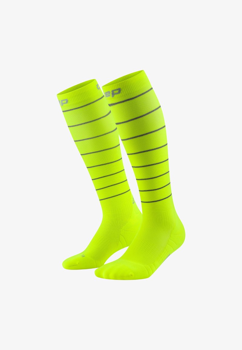Kniehohe Kompressionssocken in leuchtendem Neon-Gelb mit horizontalen schwarzen Streifen, glatter Textur und verstärkten Zehen- und Fersenbereichen.