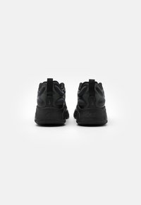 Svarta träningsskor med en slät textur, vadderad baksida och dragflikar. Designade med en tjock sula och subtilt präglad logotypdetalj.