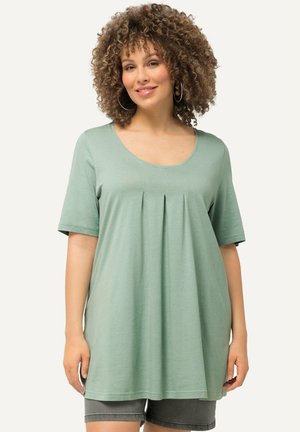 Top verde menta a maniche corte con scollo a barca e dettaglio plissettato frontale. Realizzato in morbido cotone, cade sotto i fianchi.
