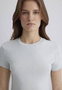 Light blue, short-sleeved t-shirt with a round neckline. Smooth texture, fitted design, minimal stitching details, and no visible patterns.