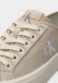 Baskets Calvin Klein en daim beige clair avec lacets blancs, œillets et logo sur le côté et la languette.