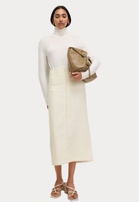 Vit polokrage, texturerad krämfärgad midiklänning, beige handväska med kedjedetalj och sandaler med remmar. Fokusera på neutrala färger och tyger.
