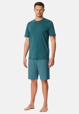 Türkisfarbenes Baumwoll-T-Shirt mit kurzen Ärmeln, kombiniert mit türkisfarbenen Shorts mit einem Diamantmuster. Beide Kleidungsstücke haben eine lockere Passform.