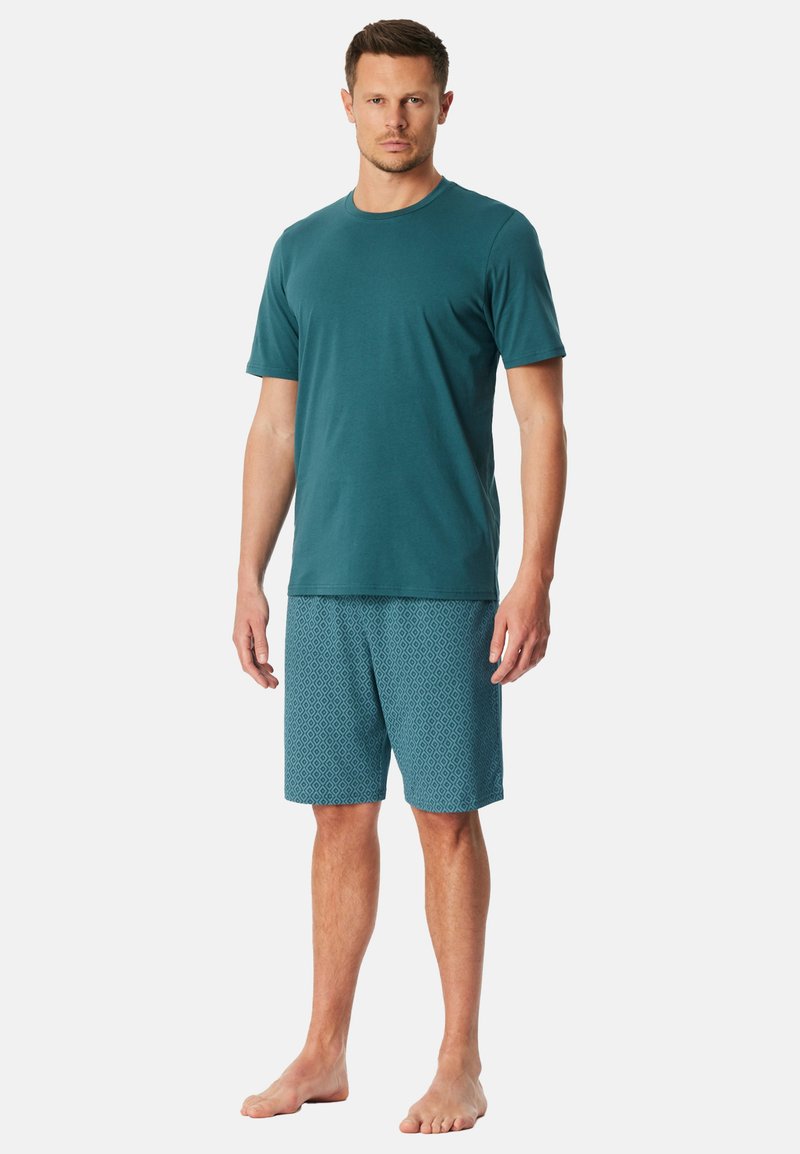 Türkisfarbenes Baumwoll-T-Shirt mit kurzen Ärmeln, kombiniert mit türkisfarbenen Shorts mit einem Diamantmuster. Beide Kleidungsstücke haben eine lockere Passform.