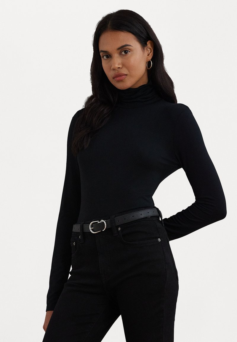 Zwarte langmouw top met col en een strakke fit. Draagt met zwarte high-waisted jeans en een zwarte riem met een zilveren gesp.