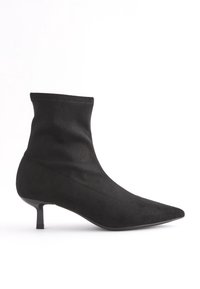 Czarne zamszowe botki za kostkę z ostrym noskiem i smukłym obcasem. Projekt charakteryzuje się dopasowaną cholewką i gładką teksturą.