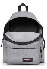 Grau farbener Stoffrucksack mit rundem oberen Ende, schwarzen Akzenten, verstellbaren Trägern und einer Fronttasche. Verfügt über einen Zugverschluss und ein Markenpatch.