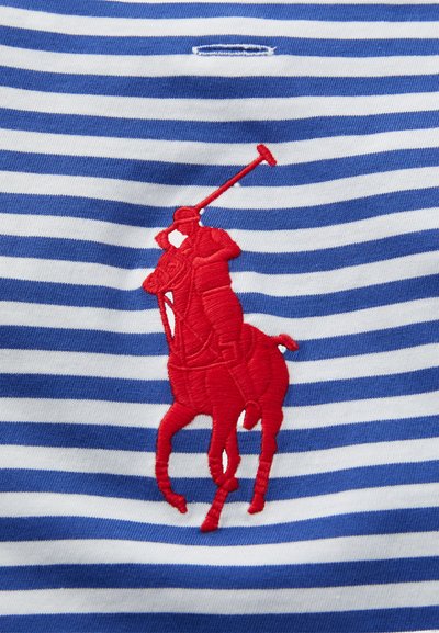 Joueur de polo rouge brodé sur cheval tenant un maillet sur un tissu rayé horizontal bleu et blanc.