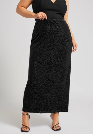Falda maxi de estampado de leopardo negro hecha de tejido texturizado, con una cintura ajustada y una silueta fluida, combinada con sandalias negras de tiras.