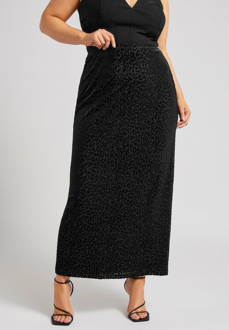 Schwarzer Leopardenmuster-Maxirock aus strukturiertem Material, mit einem taillierten Bund und einer fließenden Silhouette, kombiniert mit schwarzen Sandalen mit Riemchen.