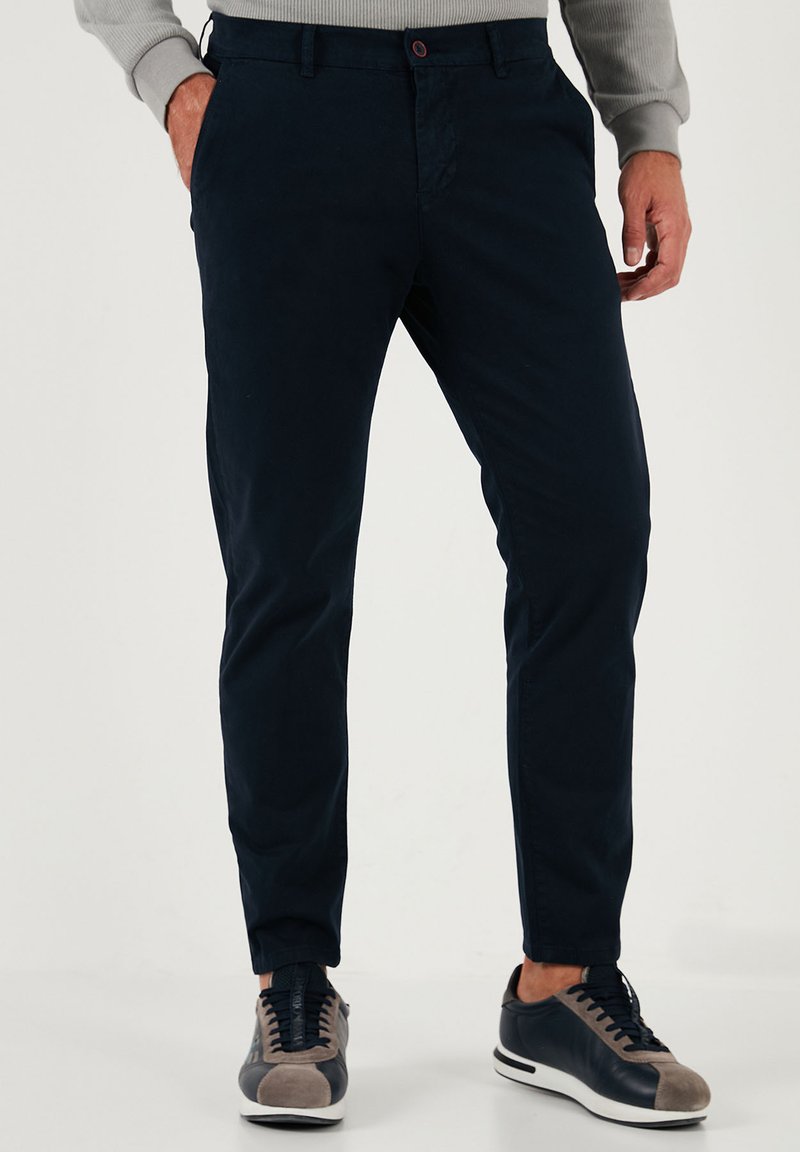 Tengerészkék chino nadrág, pamut keverék anyagból, slim fit szabással, lapos elülső résszel, oldalsó zsebekkel és egy gombos záródással.