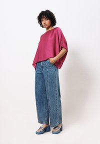 Korte mouw fuchsia top met een losse fit, gecombineerd met wijde blauwe denim jeans en blauwe chunky hak sandals.