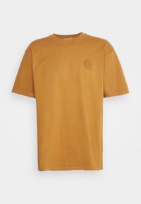 Rust-colored short-sleeve crew neck t-shirt with a small decorative emblem on the left chest against a plain background.