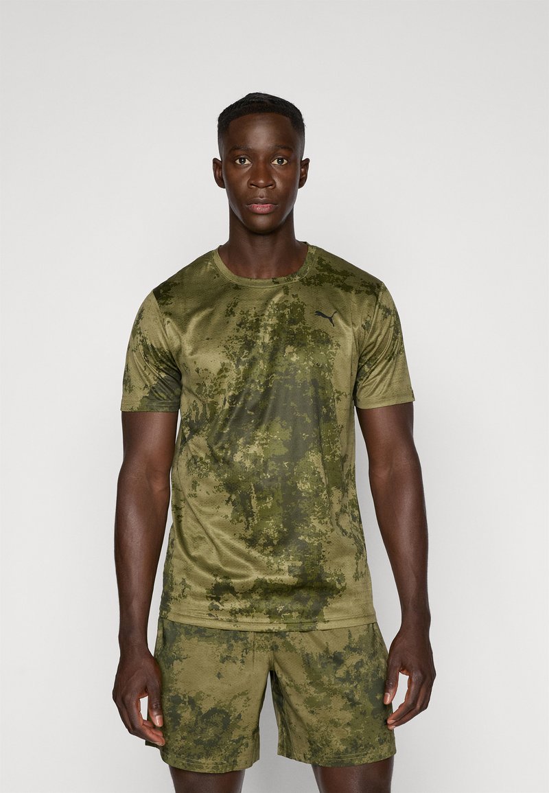 Olijfgroene sportt-shirt en shorts met een gestructureerd camouflagepatroon. Gemaakt van lichte stof en heeft het Puma-logo op de borst.