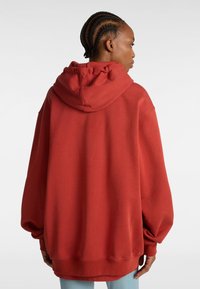 Roter übergroßer Kapuzenpullover mit Kapuze, langen Ärmeln und gerippten Bündchen. Aus weichem, strukturiertem Stoff gefertigt, mit einer lockeren Passform.