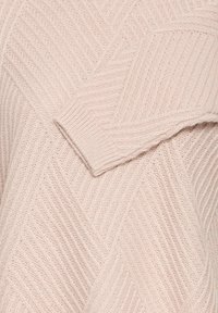 Ljusrosa stickad tröja med ett diagonalt ribbat mönster som har en lös passform och texturerad tyg. Mjuk, avslappnad design med bred rundhals.