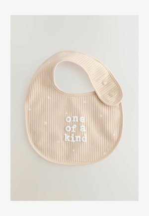 Bež ribaga bibi, millel on valged kolmnurgamustrid ja tekst "üks ja ainus" kõrgete valgete tähtedega. Küljel on nupukinnitus.