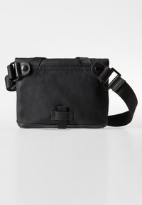 Black crossbody bag made of durable fabric, featuring a fold-over design, adjustable strap, snap closure, and minimalistic hardware accents.