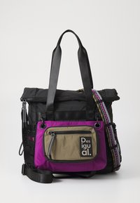 Musta nailonlaukku, jossa on violetit ja oliivinvihreät yksityiskohdat, vetoketjullinen etutasku, säädettävät hihnat ja koristeelliset metalliosat.