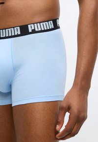 Svetlomodré boxer šortky s čiernym elastickým pásom, na ktorom je v bielej farbe vytlačené "PUMA". Tkanina vyzerá hladko s minimom šitia.
