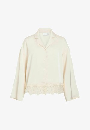 Kremowa bluzka z kołnierzykiem w stylu marynarskim, zapinana na guziki, z długimi rękawami. Posiada ozdobną koronkową lamówkę na dole. Miękka, gładka tkanina.
