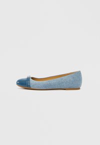 Bailarina azul vaquera con puntera brillante y pequeño detalle decorativo. La suela es plana con un acabado texturizado marrón claro.