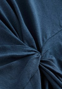 Námornícky modrý textil s uzlovým stredovým detailom, s jemnou textúrou a hladkým povrchom, zobrazuje jemné záhyby a skláňania.