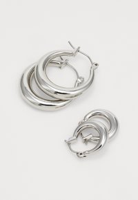 Silver hoop earrings in two sizes, featuring a polished finish, circular shape, and secure clasp design. Texture is smooth and reflective.