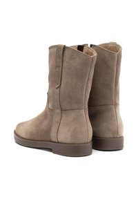 Botas de ante marrón hasta el tobillo con punta redondeada, paneles laterales elásticos y un acabado texturizado. La suela es plana y está fabricada con caucho duradero.