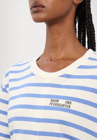 T-shirt en coton rayé crème avec des rayures horizontales bleu clair. Il présente un col rond et le texte noir "BAUM UND PFERDGARTEN."