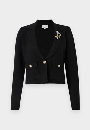 Svart cropped blazer med strukturert strikkefinish, med snippkrage, to frontlommer, gullknappdetaljer og en dekorativ brosje.
