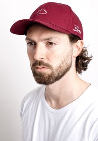Maroon cap with white cloud logo and embroidered brand name. Cotton fabric with curved brim, featuring a structured design and adjustable back.