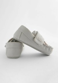 Light gray moccasin-style shoes with velcro strap, soft suede material, gathered stitching at the front, and flat rubber sole.