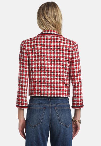 Rote und weiße kariertes, kurzes Jackett mit dreiviertellangen Ärmeln, strukturiertem Stoff und einem detailreichen, gewellten Saum. Kombiniert mit blauen Denim-Jeans.