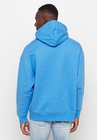 Felpa con cappuccio blu, realizzata in morbido cotone, con una vestibilità rilassata, polsini e orlo a costine, e un grande cappuccio regolabile.