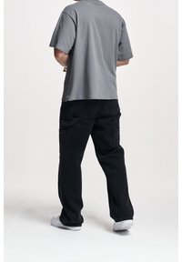 Szara bawełniana koszulka z luźnym krojem i krótkimi rękawami, w połączeniu z czarnymi spodniami cargo z bocznymi kieszeniami i prostym krojem nogawki.