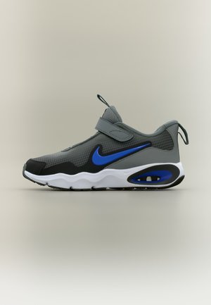 Chaussure de sport grise et noire avec logo Nike bleu, semelle blanche avec coussin d'air et bride Velcro, présentée en profil latéral sur fond neutre.