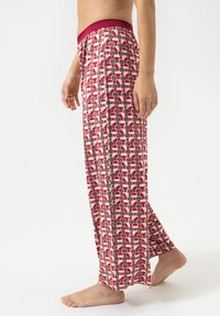 Pantalons de pyjama légers et à motifs, avec une ceinture bordeaux et un motif de cercles rouges, blancs et marron. Texture douce, coupe décontractée.