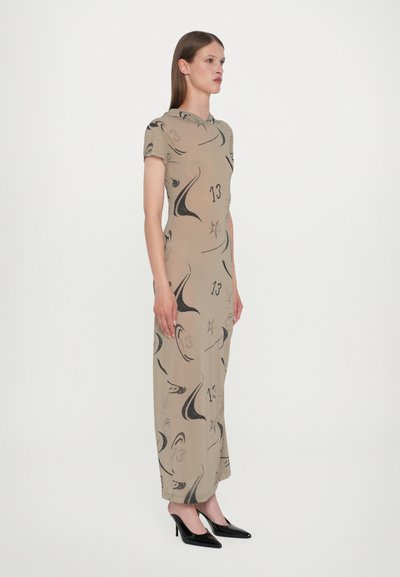 Vestido beige con mangas cortas, diseño ajustado al cuerpo, patrones abstractos en negro y dobladillo que llega a los tobillos, combinado con tacones altos negros.