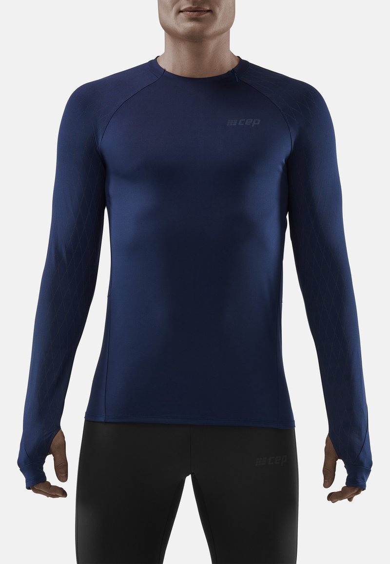 Marineblaue Langarm-Sportshirt mit glatter Textur, Raglanärmeln und dezentem Rautenmuster an den Ärmeln. Logo auf der Brust präsentiert.