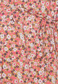 Vestido floral com um fundo mostarda, apresentando flores em tons de rosa, branco e azul-marinho. Inclui um laço na cintura e pregas discretas.