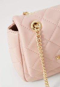 Ροζ τσάντα ώμου από συνθετικό δέρμα με καπιτονέ σχέδιο, χρυσή αλυσίδα και λεπτομέρειες με γατζάκια. Διαθέτει κλείσιμο με κούμπωμα και ομαλή υφή.