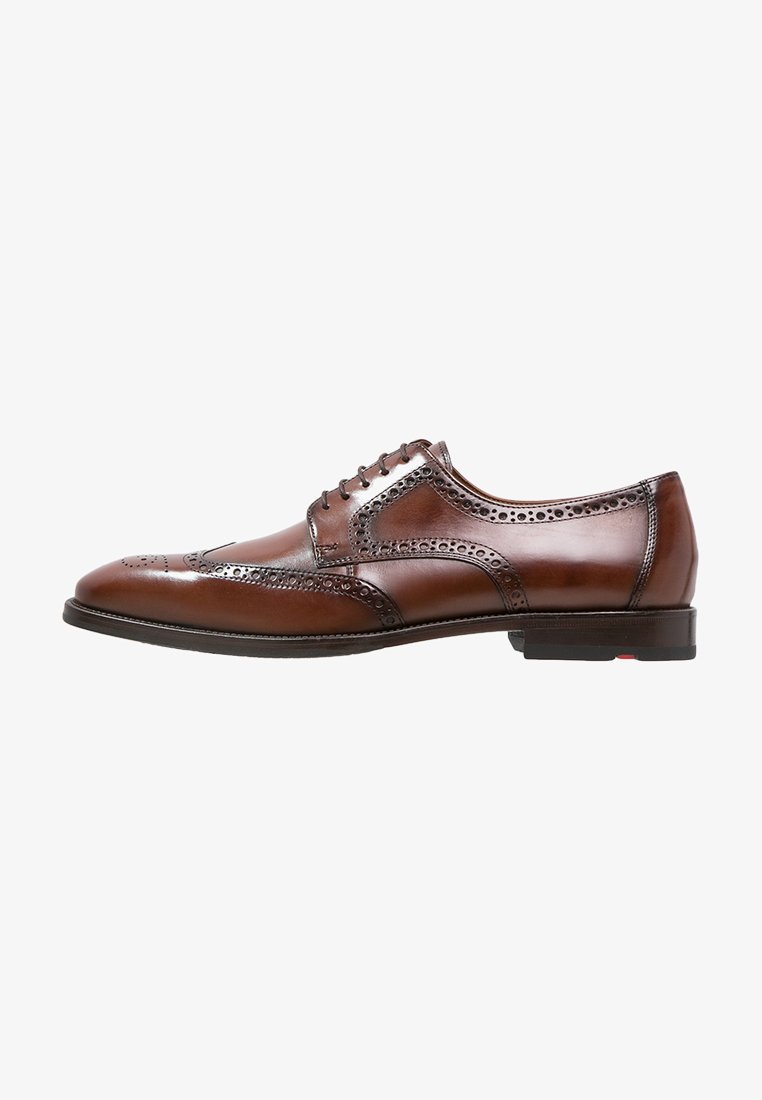 Scarpe brogue in pelle marrone con finitura liscia, perforazioni decorative, design allacciato e suola nera a profilo basso.