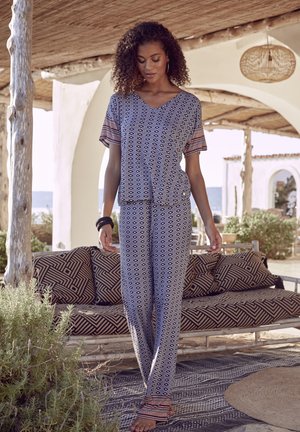 Lightweight, patterned loungewear set in navy with white geometric designs. Short-sleeve top, relaxed pants, and a soft texture. Accents in red.