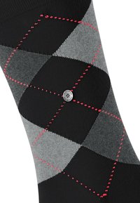 Calzino a motivo argyle nero e grigio con diamanti rossi ricamati e un bottone rotondo in metallo argentato sulla caviglia. Materiale in maglia morbida.